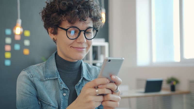 Darbuotoja žiūri į telefoną